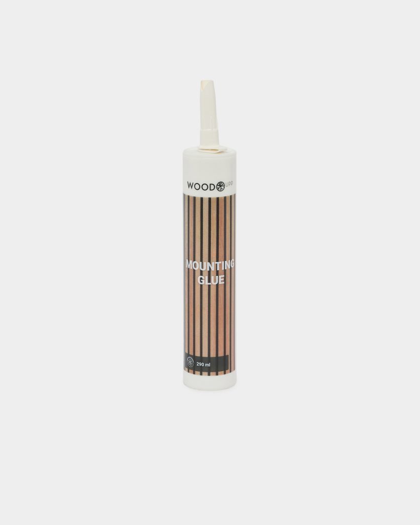 Witte WoodUpp-kartouche met spuitmondje: een 290 ml tube Mounting Glue. Etiket toont verticale houtstripprint in bruin/zwart en tekst 'MOUNTING GLUE', inclusief WoodUpp-logo bovenaan. Product staat rechtop tegen lichte achtergrond, met witte dop en smalle kunststof tuit, bedoeld voor bevestigen en monteren van houten elementen.