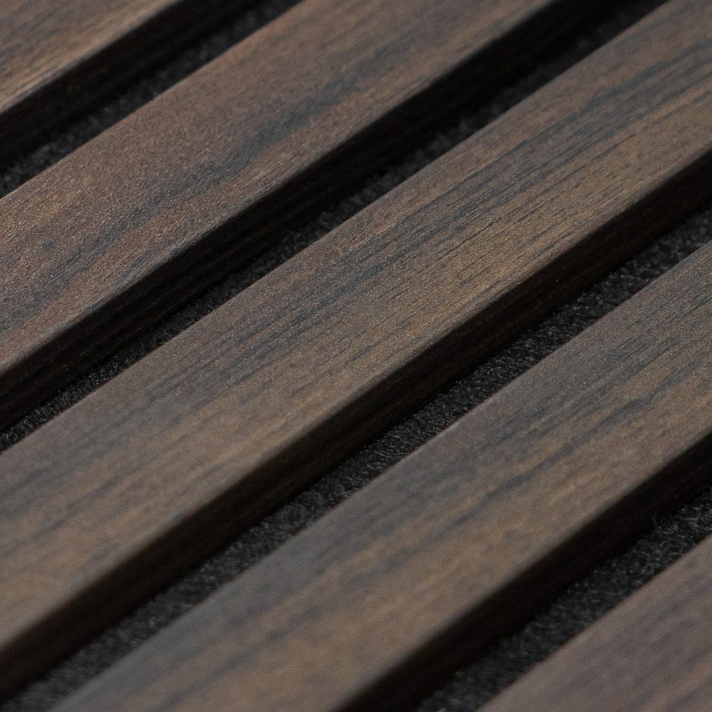 Close-up van een WoodUpp houten lattenpaneel: meerdere smalle, parallelle donkerbruine houten latten met zichtbare houtnerf en matte afwerking, geplaatst op een zwarte akoestische ondergrond. Detail toont regelmatige tussenruimtes en de warme, natuurlijke textuur van WoodUpp lattenpanelen voor wand- en akoestische toepassing.