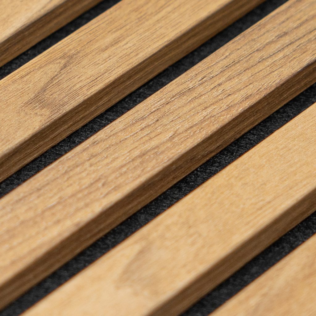 Close-up van WoodUpp houten lattenpaneel: licht eiken houten latten met zichtbare nerf, parallel geplaatst op een zwarte akoestische onderlaag. Detail toont strakke, gelijkmatige lamellen en donkere stofvoeringen tussen de latten; modern, minimalistisch akoestisch wandpaneel van WoodUpp met warme houtkleur en fijne textuur, ideaal voor woningen en kantoren.