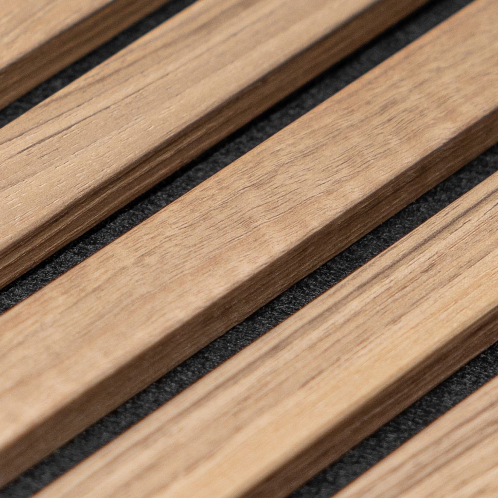 Close-up van een WoodUpp lattenpaneel: strakke, lichtbruine houten latten met zichtbare nerf, diagonaal geplaatst op zwarte, geluidabsorberende viltachtergrond. De nauw sluitende tussenruimtes en gladde afwerking tonen WoodUpp’s houten wand-/akoestische panelen in detail; natuurlijke houttekening en matte lak geschikt voor moderne interieurs.