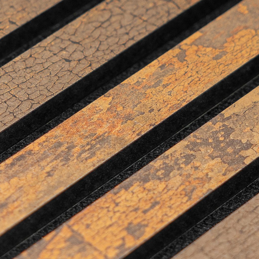 Close-up van WoodUpp lamellenpanelen: diagonale, smalle houten latten met een verweerde oranje‑bruine, craquelé‑achtige patina en matte textuur, afgewisseld door smalle zwarte voegen. Het product toont duidelijke houtnerf, subtiele kleurvariaties en antiek-look afwerking, geschikt als decoratieve wand- of meubelbekleding van WoodUpp.