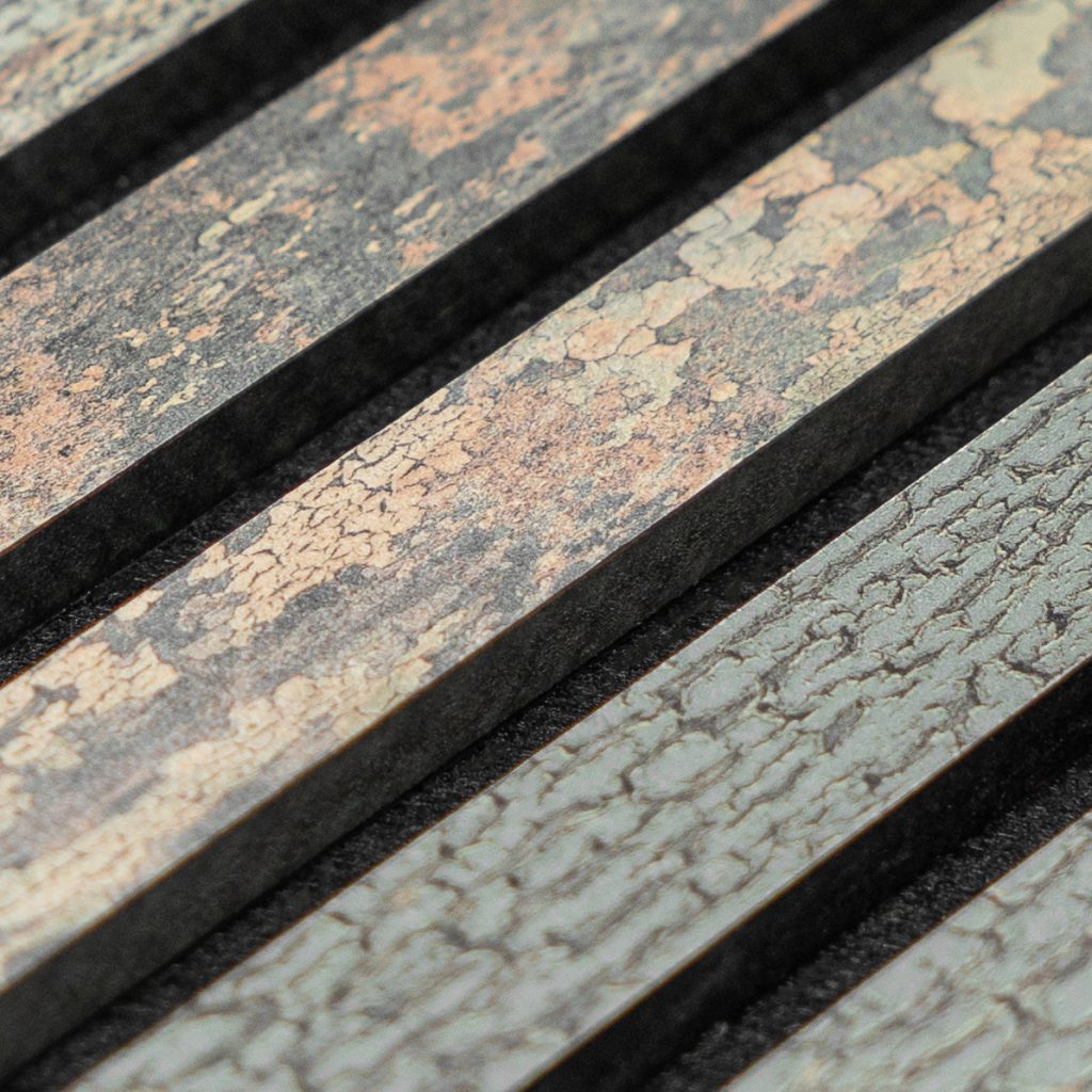 Close-up van WoodUpp houten latten: smalle, parallel geplaatste lamellen met een verweerd, craquelé-achtig patroon in grijzige, beige en kopertinten. De WoodUpp-stroken hebben rechthoekige randen, een matte, licht korrelige, gebarsten verftextuur en donkere tussenruimtes, met subtiele kleurvariaties en natuurlijk ogende verwering; dunne profielen suggereren toepassing als sierlatten.