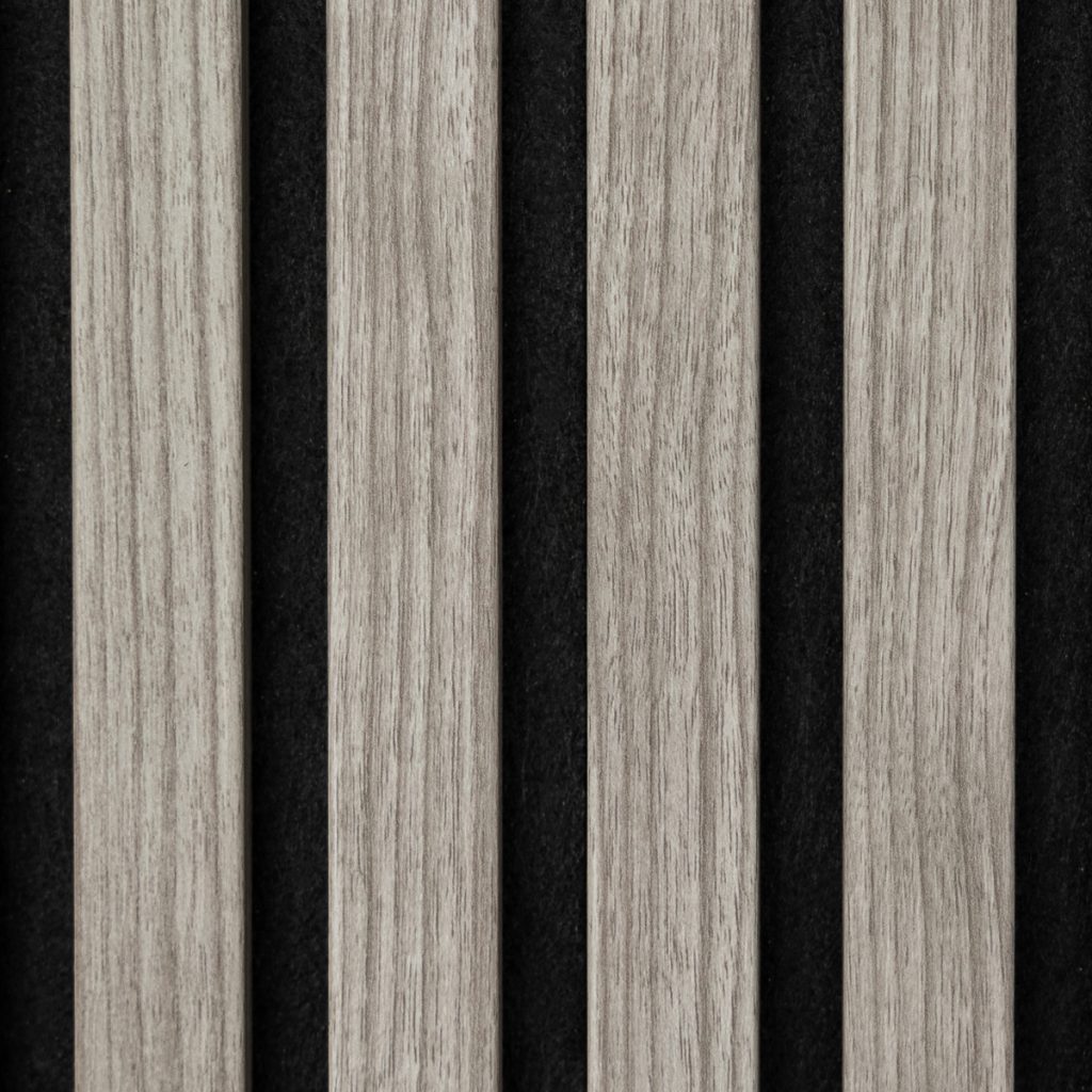 Close-up van een WoodUpp lamellenpaneel met vijf smalle, verticale lichtgrijze houten latten met zichtbare nerf, geplaatst op een zwarte vilten achterwand. De WoodUpp houtlatten tonen een glad, licht geaderd oppervlak en creëren een strak, akoestisch en decoratief lamellenpatroon met hoogwaardige afwerking en subtiele kleurvariatie.
