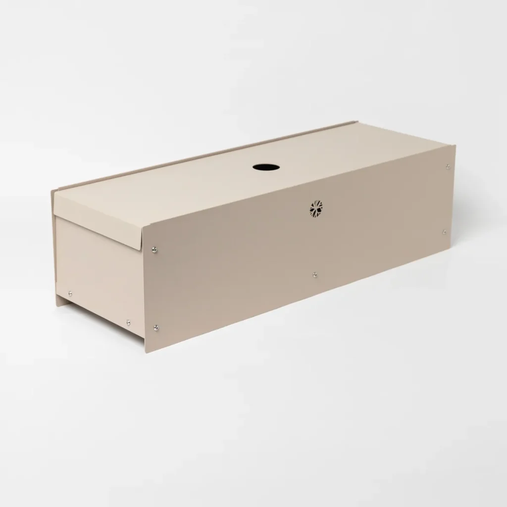 Beeld van een WoodUpp beige houten vangdoos: langwerpige, rechthoekige kist met afneembaar deksel, ronde instapopening bovenop, ventilatiegat en zichtbare schroeven. Strak, minimalistisch ontwerp voor het tijdelijk vangen/opvangen van kleine knaagdieren; neutrale zandkleur, compact formaat, geschikt voor binnen- en buitengebruik.