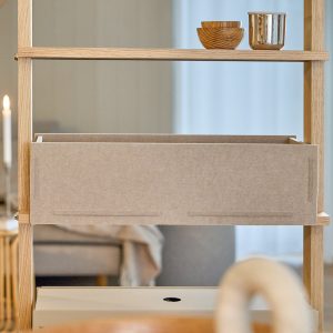 WoodUpp houten open rek van licht eiken met smalle horizontale plankjes, waarin een beige vilten opbergbox/lade van WoodUpp hangt. Op het bovenste plankje twee kleine houten schaaltjes en een glanzende metalen beker als decoratie, praktische lade voor losse spullen en accessoires.